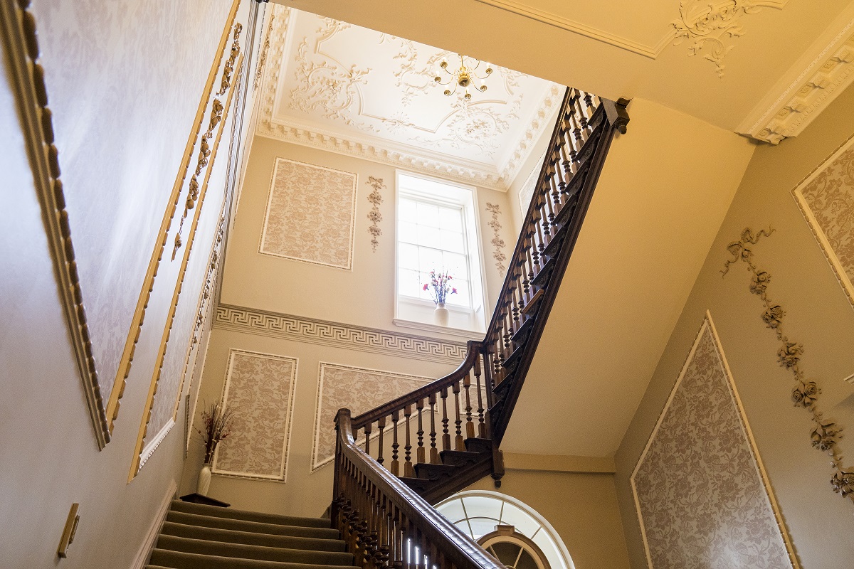 an ornate staircase with wooden railings and carpeted floors