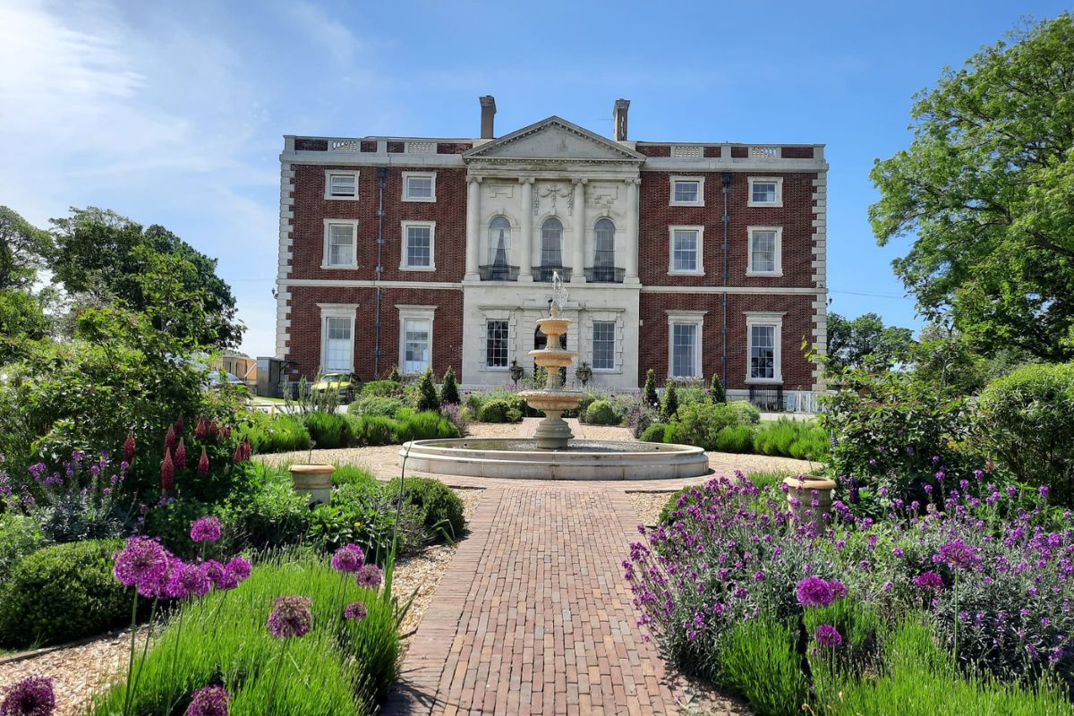 A grand manor house situated behind a large fountain