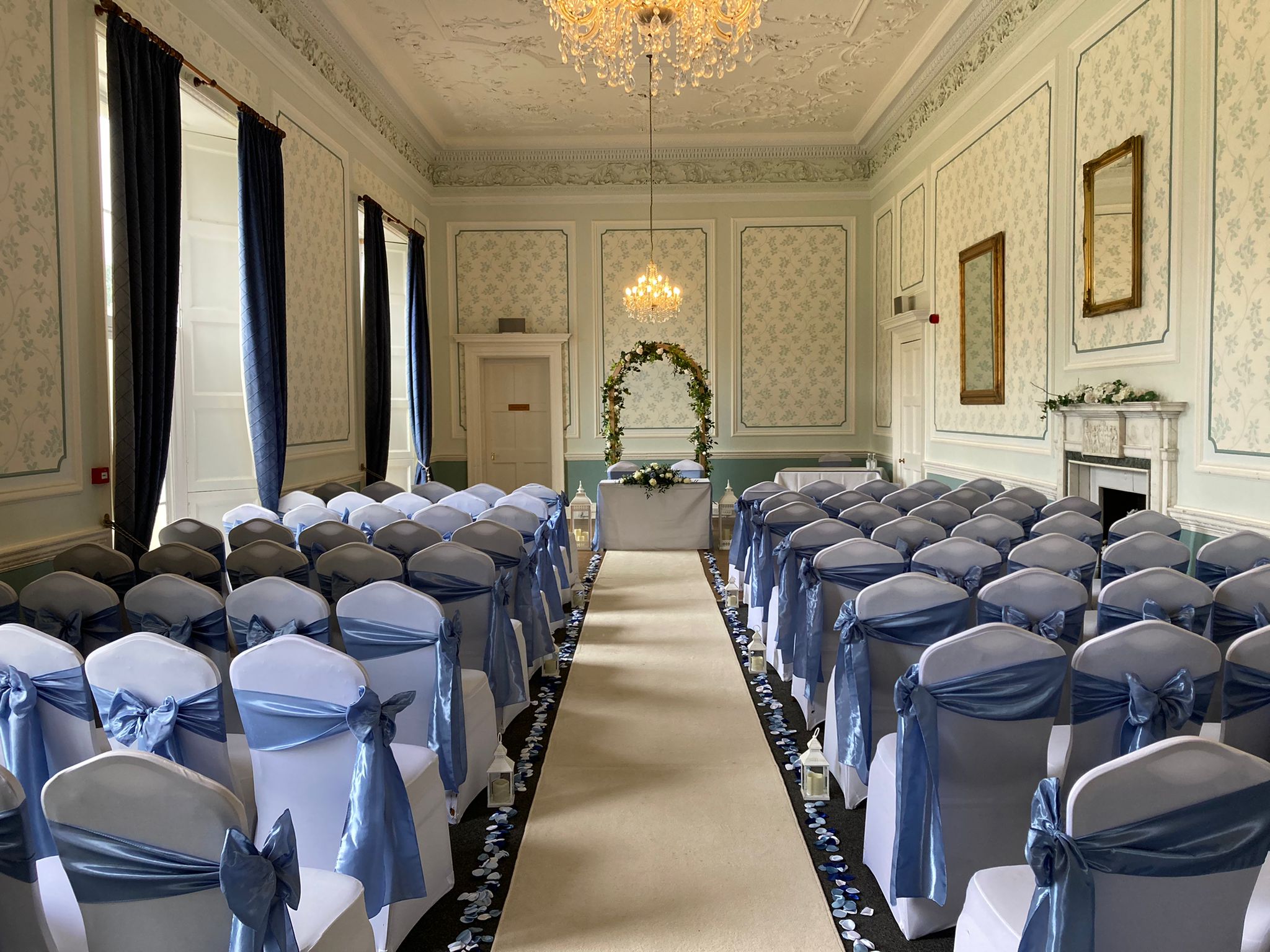 The Old Library room set up for a wedding ceremony with a flower arch in the middle of the aisle