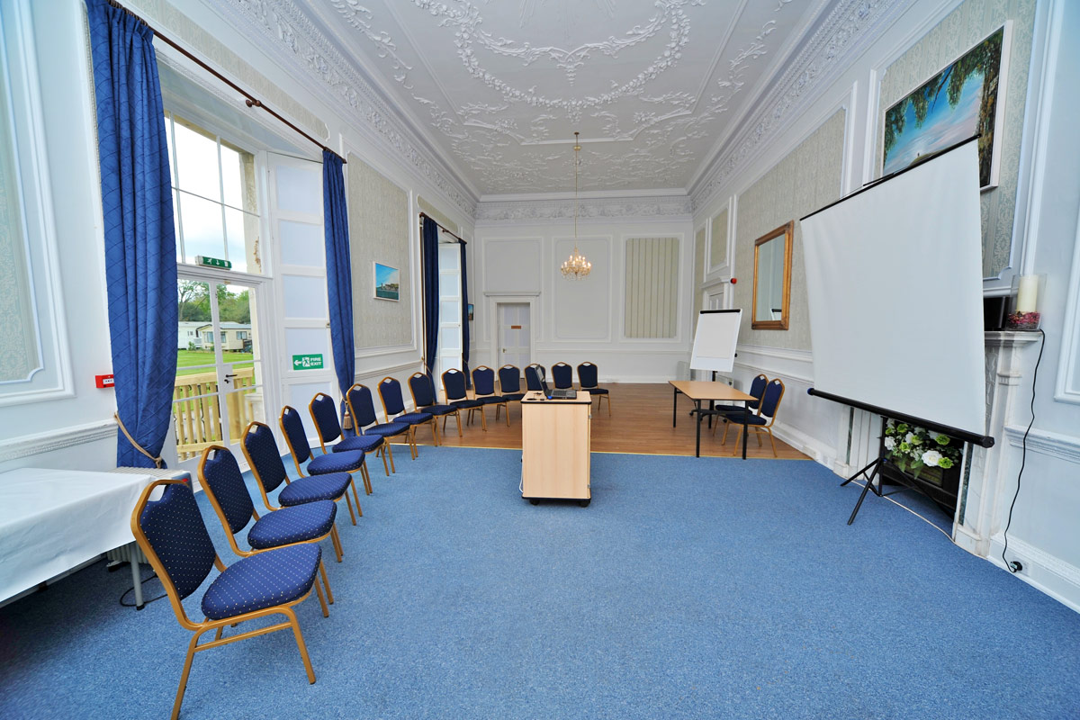 A large room set up with a single row of chairs lined up in a semicircle facing a large projector screen